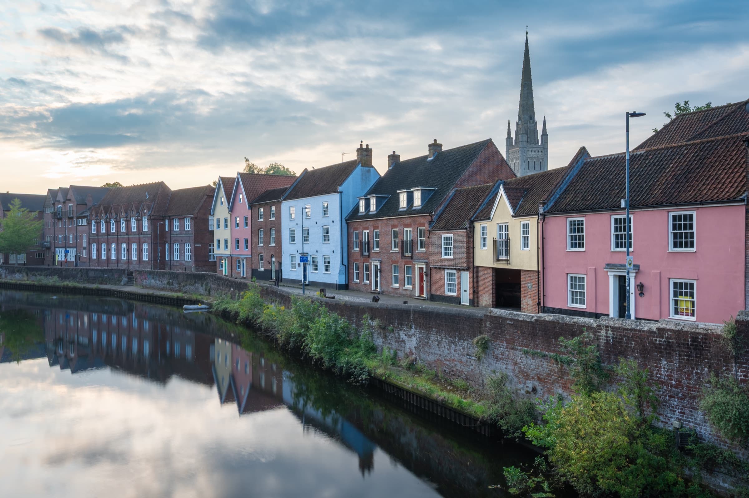 Norwich riverside at dawn, with the cathedral spire behind a row of colourful houses