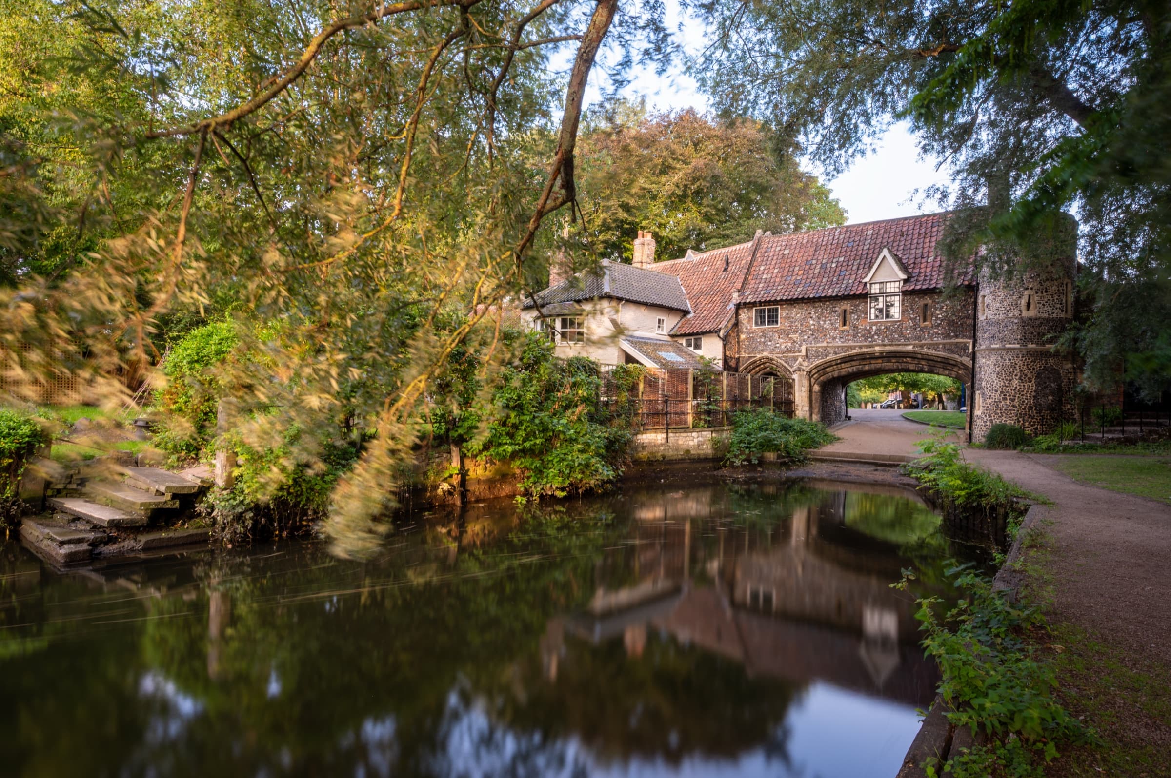 A flint gatehouse spanning the riverside path in Norwich